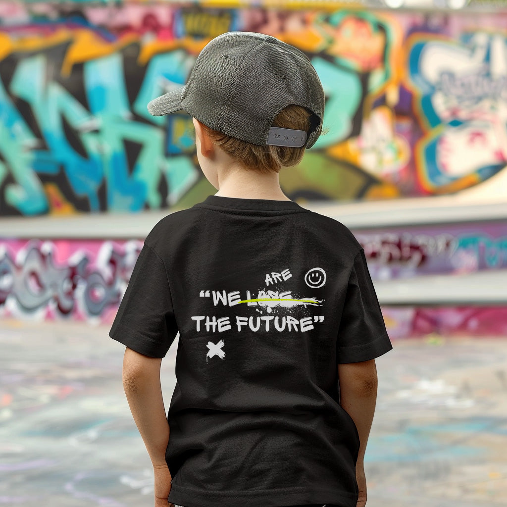 a young boy standing in front of a graffiti covered wall